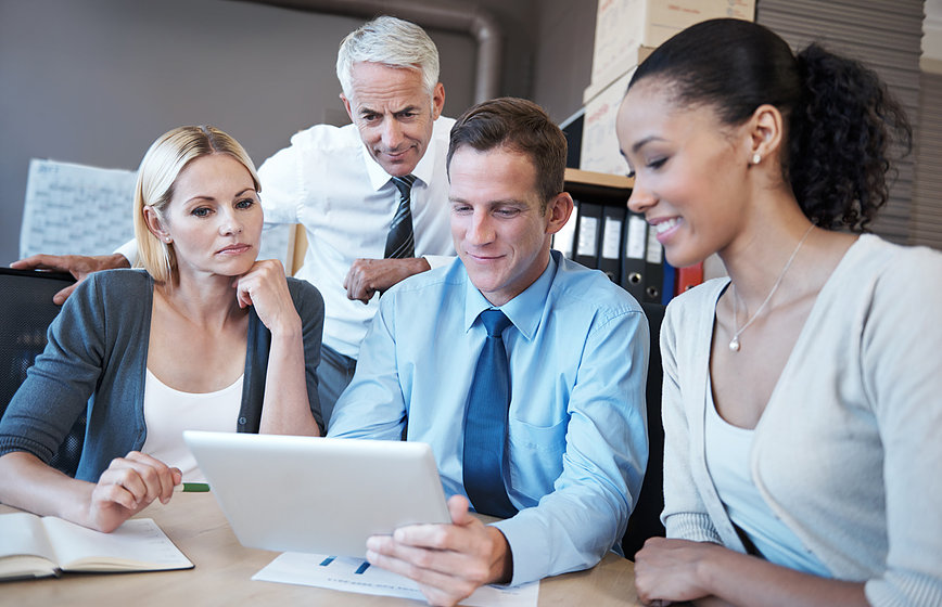 Shot of a group of business people sitting together while looking at a digital tablet